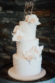 a three tiered wedding cake with flowers on top