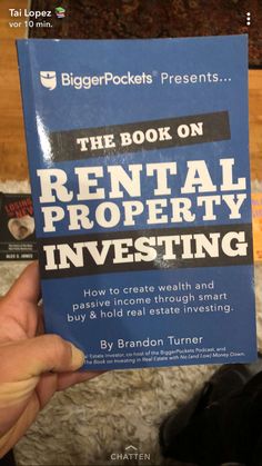 the book on rental property investing is being held up by someone's hand in front of them