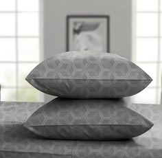 three pillows stacked on top of each other in front of a bed with two vases