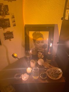 a woman is looking at her reflection in a mirror with candles and food on the table