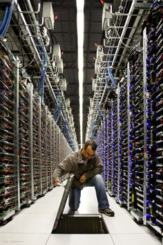 a man is kneeling down in the middle of a server room