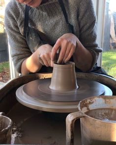 a woman is making a vase out of clay