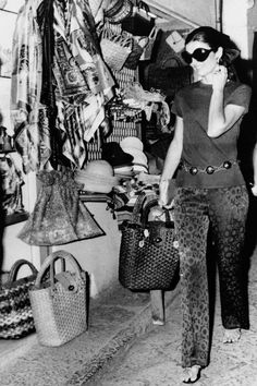 black and white photograph of woman talking on cell phone in clothing store with handbag