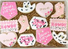 some decorated cookies in a box with pink and white designs on them for someone's special occasion