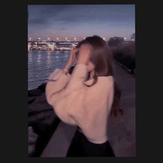 a woman is walking along the water at night