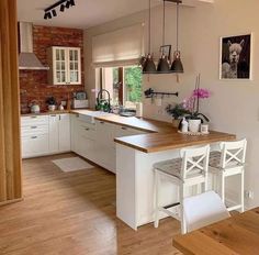 a kitchen with wooden floors and white cabinets is seen in this image from the dining room