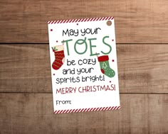 a christmas card with stockings hanging from it's side on a wooden background that says, may your toes be cozy and your spirits bright merry christmas