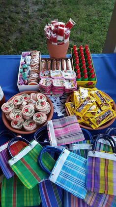 an assortment of desserts and candy displayed on a blue table cloth covered picnic table