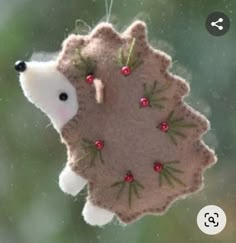 an ornament shaped like a hedge hanging from a tree branch with berries on it