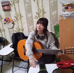 a woman sitting in a chair holding an acoustic guitar