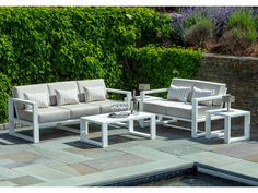 a couch and table sitting on top of a stone patio next to a swimming pool