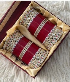 two red and gold decorative pillows in a box