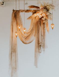 a chandelier with lights hanging from it's sides and sheer fabric draped over it