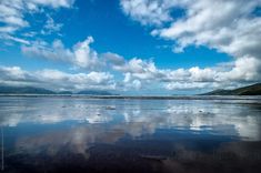 clouds are reflected in the wet sand at low tide