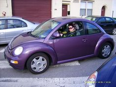 a man driving a purple car in a parking lot