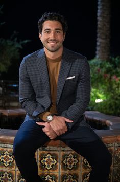 a man sitting on top of a wooden bench next to a fountain in the dark