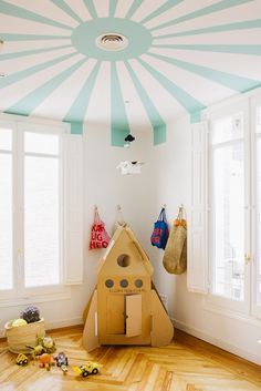 a child's room with a cardboard house on the floor