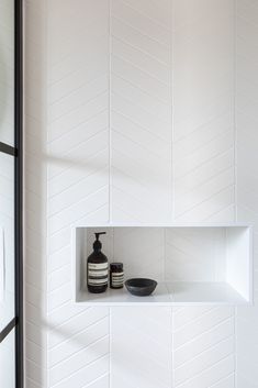 a white shelf with two black vases on it