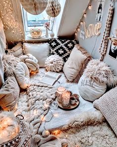 a room filled with lots of pillows and blankets on top of a bed covered in lights