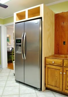 a stainless steel refrigerator sitting in the middle of a kitchen next to cabinets and drawers