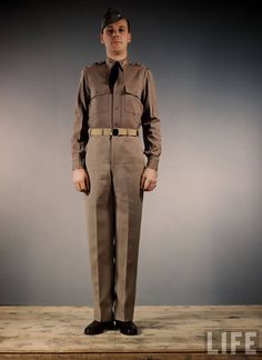 a man in a uniform standing on a wooden floor with his hands in his pockets