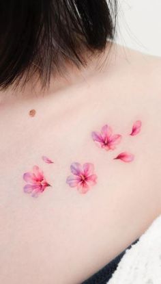 a woman with pink flowers on her shoulder and chest tattooing it's back