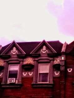 an old brick building with many windows and decorations on the top level, under a cloudy sky