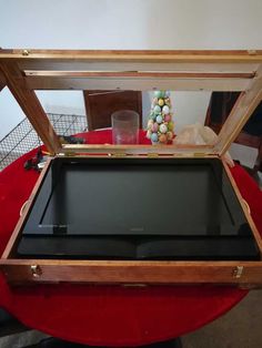 an open wooden box on top of a red cloth covered table with candy in it