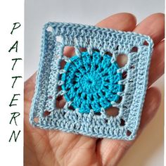 a crocheted square is shown in the palm of a person's hand