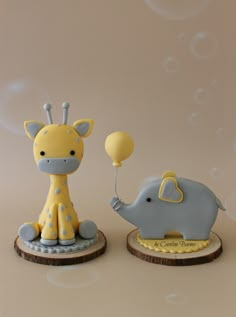 two small figurines that look like giraffes and an elephant with balloons