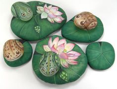 four green leaves with flowers painted on them and two toades sitting on top of each other