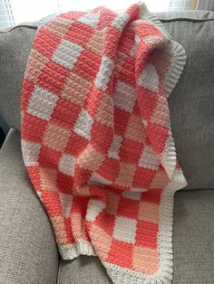 an orange and white blanket sitting on top of a couch next to a gray sofa