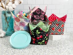 several colorful bags and containers sitting on a counter top next to cotton balls, paper towels, and other decorative items