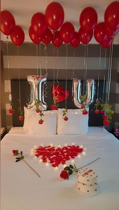 the bed is decorated with red balloons and streamers, which spell out i love you