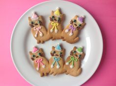 four decorated cat cookies on a white plate