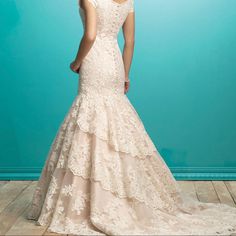 a woman in a wedding dress standing on a wooden floor with her back turned to the camera