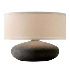 a lamp that is sitting on top of a white surface with a beige shade over it