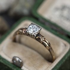 an engagement ring in a box with two diamonds on the top and one diamond at the bottom