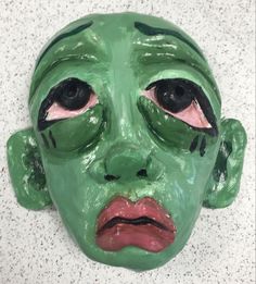 a close up of a green mask with black eyes