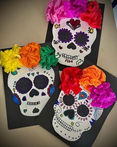 three paper plates decorated with sugar skulls and colorful flowers on top of each plate are sitting on a table