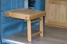 a small wooden table sitting in the back of a blue truck with it's door open