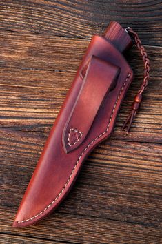 a leather sheath with a chain hanging from it's side on top of a wooden table