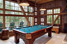 a pool table in the middle of a room with lots of windows and pictures on the walls