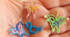 three small crocheted butterflies sitting on someone's palm, one is green and the other is blue