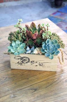 a wooden box filled with succulents and plants on top of a table