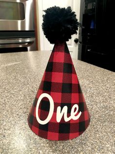 a red and black party hat with the word one on it sitting on a kitchen counter