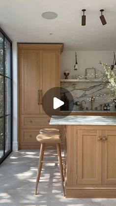 a kitchen with wooden cabinets and stools in the center, an island countertop is surrounded by glass doors