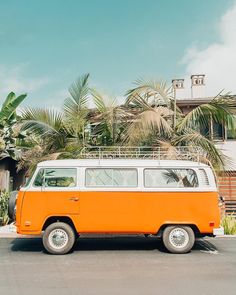 an orange and white van parked in front of a house with palm trees behind it