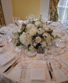 the table is set with white flowers and silverware for an elegant wedding reception or special event