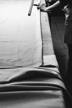 a man standing next to a bed with sheets on it and a knife in his hand